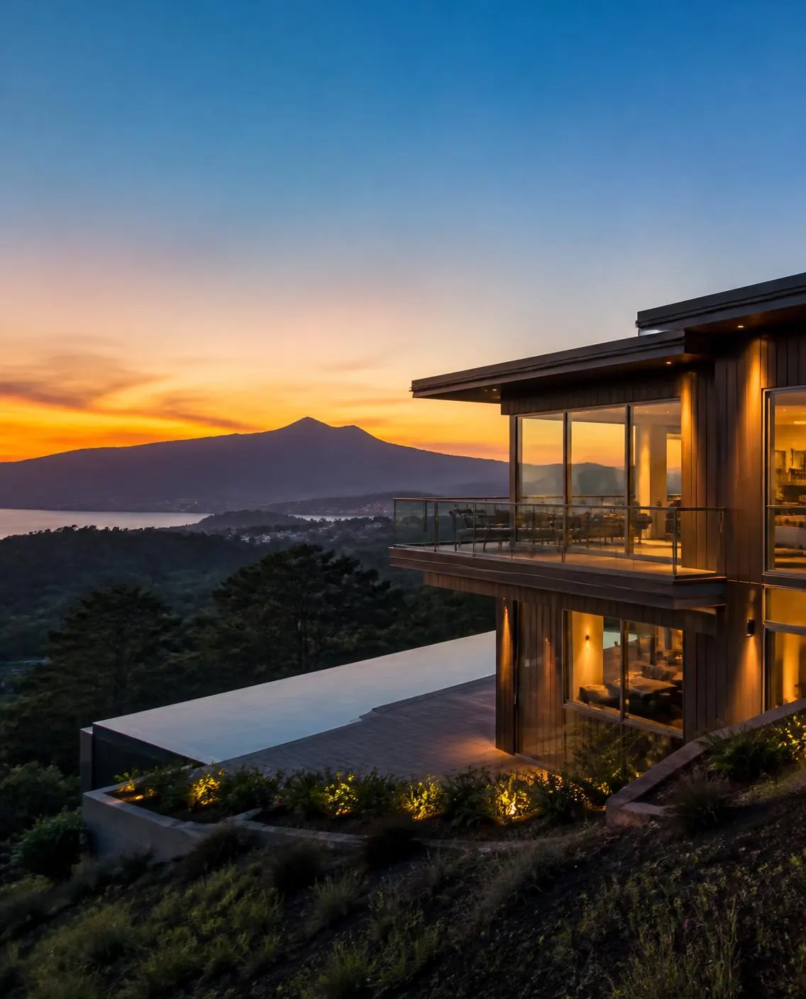 Modern residence at dusk, Marin hillside, interior lights on
